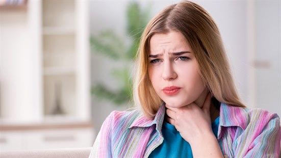 Illustrasjonsbilde av en ung kvinne som er plaget og tar seg til halsen.