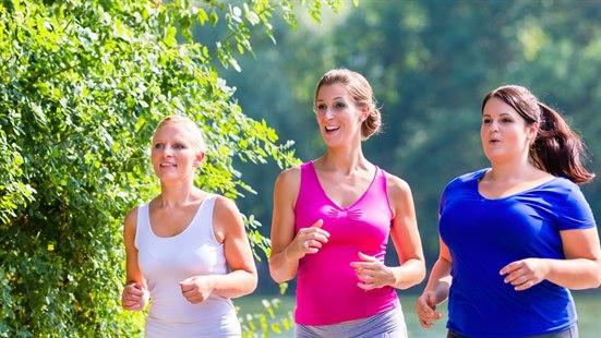 Tre kvinner jogger sammen. Grønt bladverk og grønne omgivelser i bakgrunnen.