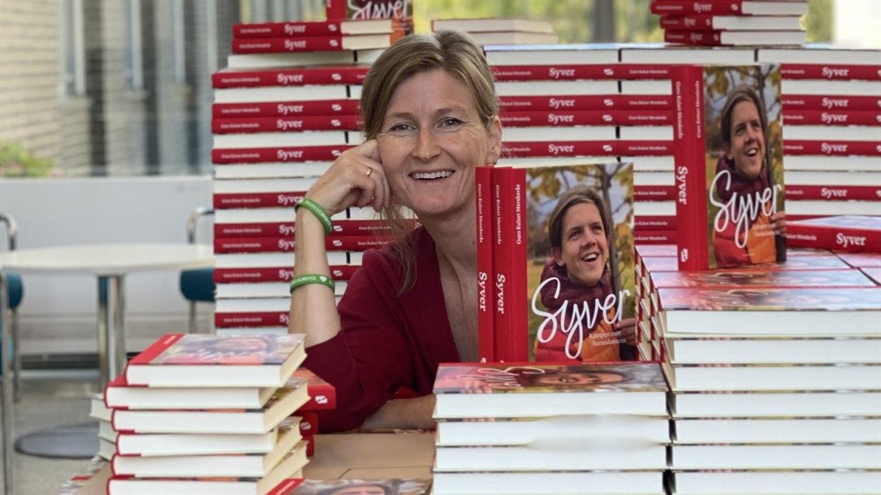 Fotografiet viser forfatteren Guro Kulset. Hun står midt blant bunker av boken hun har gitt ut, Boka om Syver. Kampen mot barnedemens.