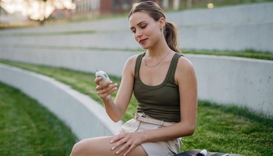 Ung, sunn kvinne leser av blodsukker utendørs