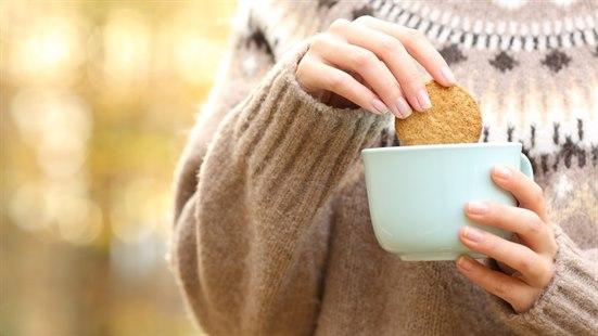 Hånd som dypper hard kjeks i kopp (kaffe?)