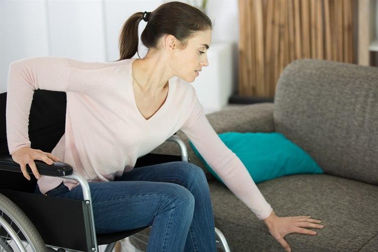 Ung dame som skal forflytte seg fra rullestolen over til sofaen