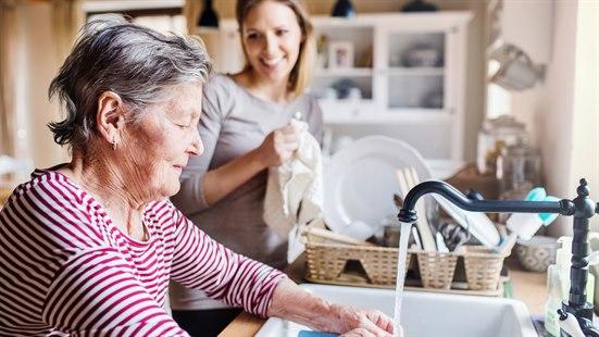 Eldre kvinne vasker opp.