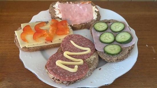 Foto av et fat med fire brødskiver med ulikt pålegg.