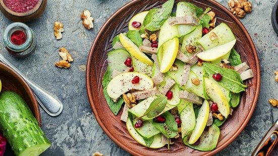 Illustrasjonsfoto av et fat med en fargerik salat. Andre salatingredienser ligger på bordet. 