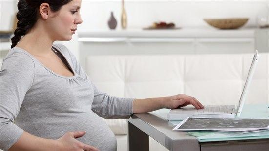 Illustrasjonsfotoet viser en gravid kvinne som sitter foran en bærbar PC