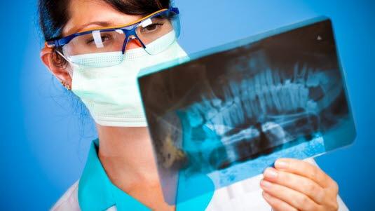 En lege holder opp et røntgenbilde av en kjeve