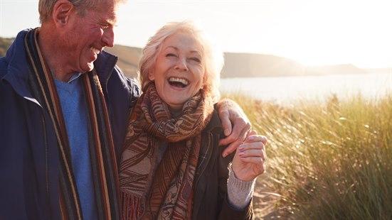 Illustrasjonsfoto av et eldre smilende par ute ved sjøen.