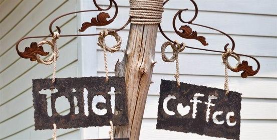 Illustrasjonsfoto: Skilt som henger fra en stolpe - ett det står "toilet" på, og ett det står "coffee" på.