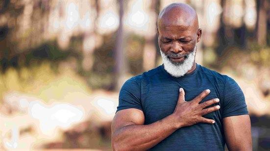 Illustrasjonsfoto: Mann som holder seg for brystet med den ene hånden. I bakgrunnen ser man trær og skog.