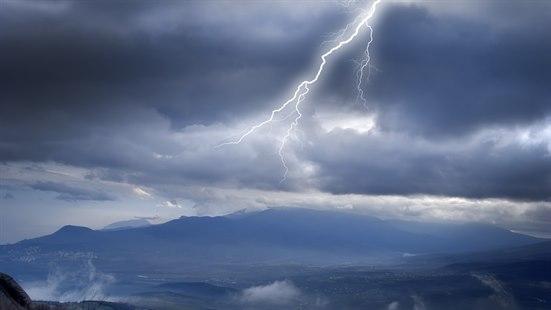 Illustrasjonsfoto av lyn på himmelen og fjell i det fjerne.