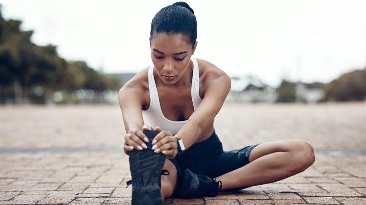 Illustrasjonsfoto av en kvinne som sitter på bakken og tøyer hamstring