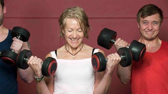 Illustrasjonsfoto: En kvinne i hvit topp står mellom to menn. Alle tre løfter vekter (bicepscurls).