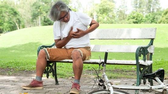 Syklist som hviler på en benk og klemmer hendene mot brystet.