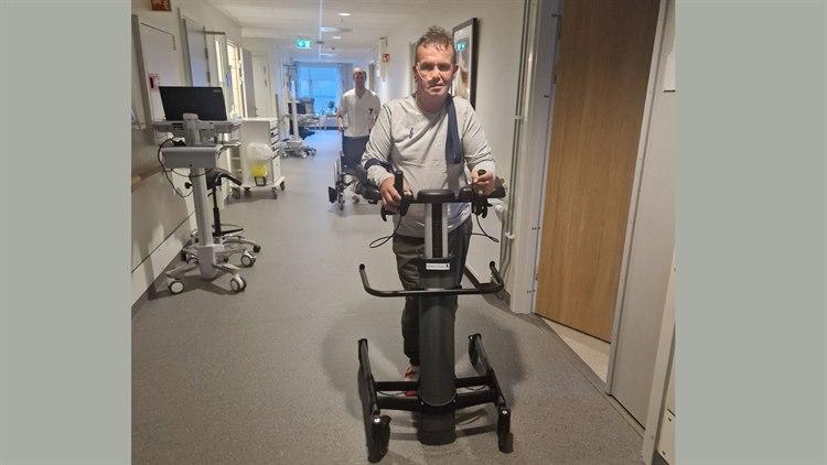 Foto viser Kjell Torstein Hagen som går nedover en korridor med gåstol.