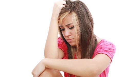 Illustrasjonsfoto av ung jente som sitter og som støtter hodet med armen.