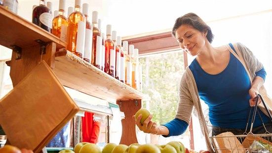 Illustrasjonsfoto: Mørkhåret kvinne som plukker opp et eple fra fruktdisken i butikken.