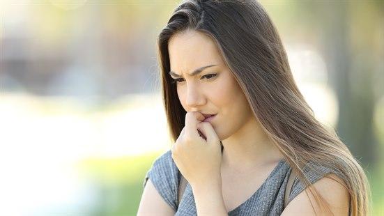 Illustrasjonsfota av ung kvinne som biter negler.