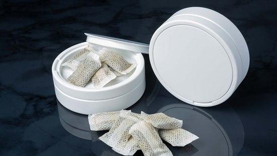 En snusboks med åpent lokk som inneholder snus, og en annen snusboks ved siden av.