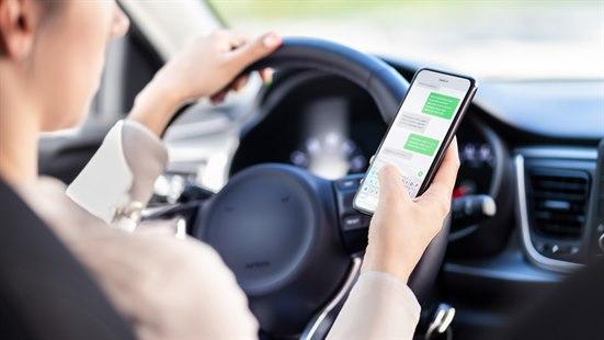 Illustrasjonsfoto av en bilsjåfør som sender melding med mobilen.