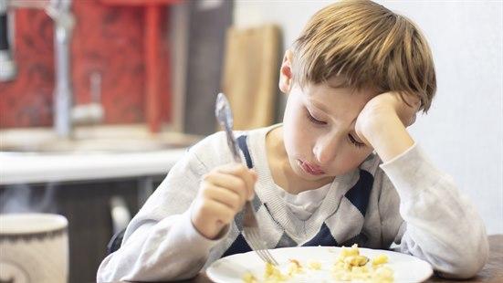 Illustrasjonsfoto av en gutt som sitter ved matbordet og pirker i maten.