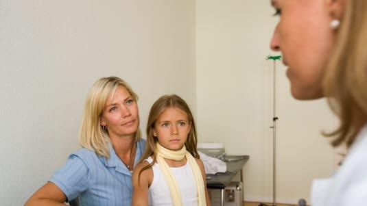 Fotoet viser en jente på ca. 9 år og en dame i 40-årene som har en konsultasjon med en kvinnelig lege i 30-årene. 