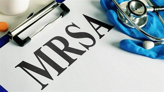 Illustrasjonsfotoet viser et ark der det står skrevet MRSA og ved siden av et stetoskop og hansker
