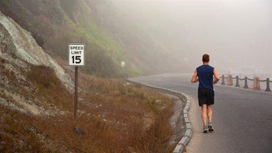 Illustrasjonsfoto av en ung mann som løper på veien, med fjell på venstre side og en sving foran løperen.