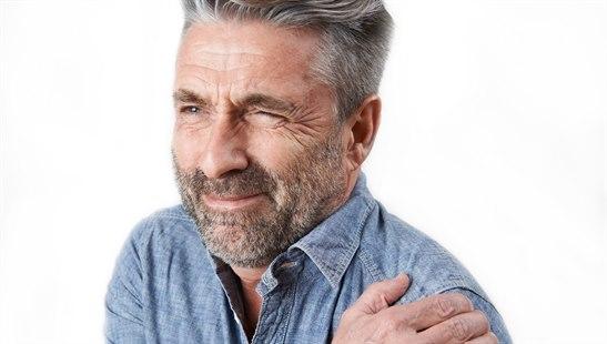 Illustrasjonsfotoet viser en voksen mann som tar seg til venstre skulder og angir smerte