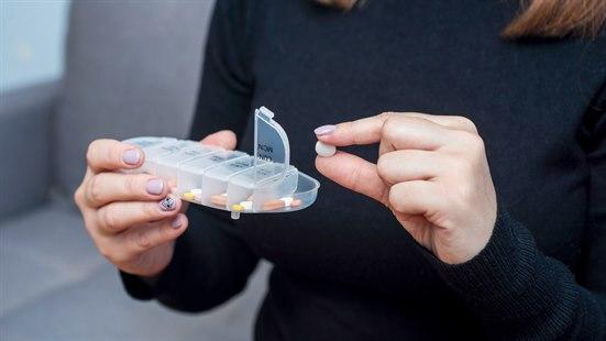 Hendene til en person som holder en dosett med tabletter