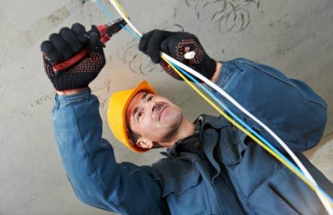 En elektriker med arbeidsutstyr som skal klippe en ledning