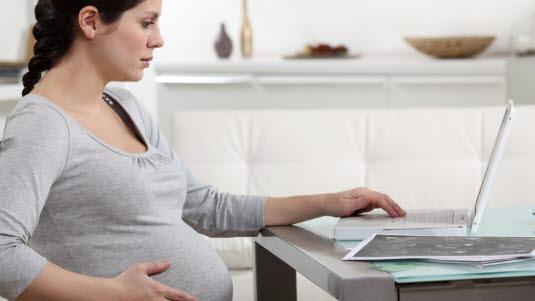Illustrasjonsfotoet viser en gravid kvinne som sitter foran en bærbar PC