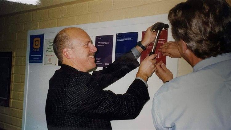 Bildet viser Terje Johannessen som spikrer opp en doktorgradsavhandling på veggen.