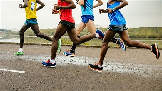 Illustrasjonsfoto av fire langdistanseløpere i shorts og singlett som løper på en landevei.