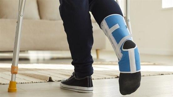 Ben  fra knærne og ned på person som går med krykker