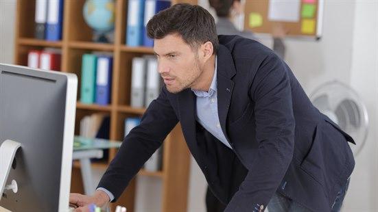 Illustrasjosnfoto av en mann som står ved kontorpulten og jobber.