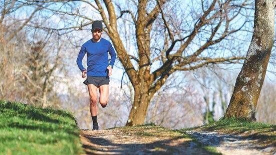 Illustrasjonsfoto av en mann i shorts som løper på en grusvei.