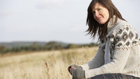 Illutrasjonsfoto av en kvinne som sitter i en eng i fint høstvær.