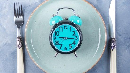 Illustrasjonsfoto av ei vekkerklokke som ligger på en tallerken med kniv og gaffel på hver sin side.
